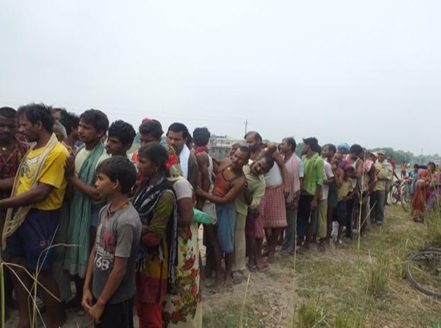 People of Paheleja Ghat village, Hajipur, wait in line for relief.
