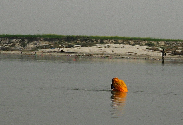 Woman bathing in shallow and polluted water in the Ganges at Kachla
