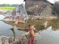 A boy stands in front of houses destroyed by flood in Karimganj district, Assam.
