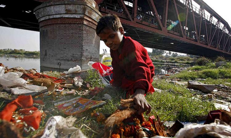 A child collects garbage at Yamuna ghat in Delhi