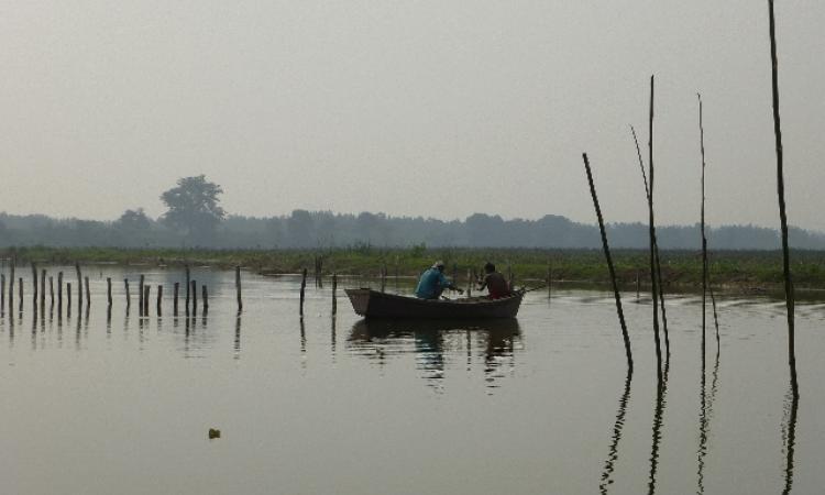 Two men fish from a small rowboat on the placid Ramganga near Harewali