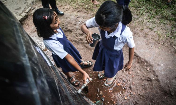 Children drinking rainwater collected in tanks at Melamati Government Junior Basic School, Jorhat (Assam).